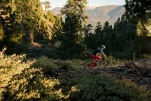 woman bikes through a beautiful mountain trail
