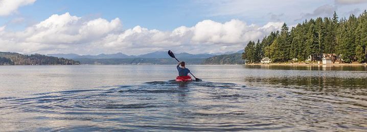 Image of an individual rowing in a kayak on a lake finding places to see in big bear