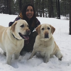 woman huddles with two golden retrievers in snow Big Bear