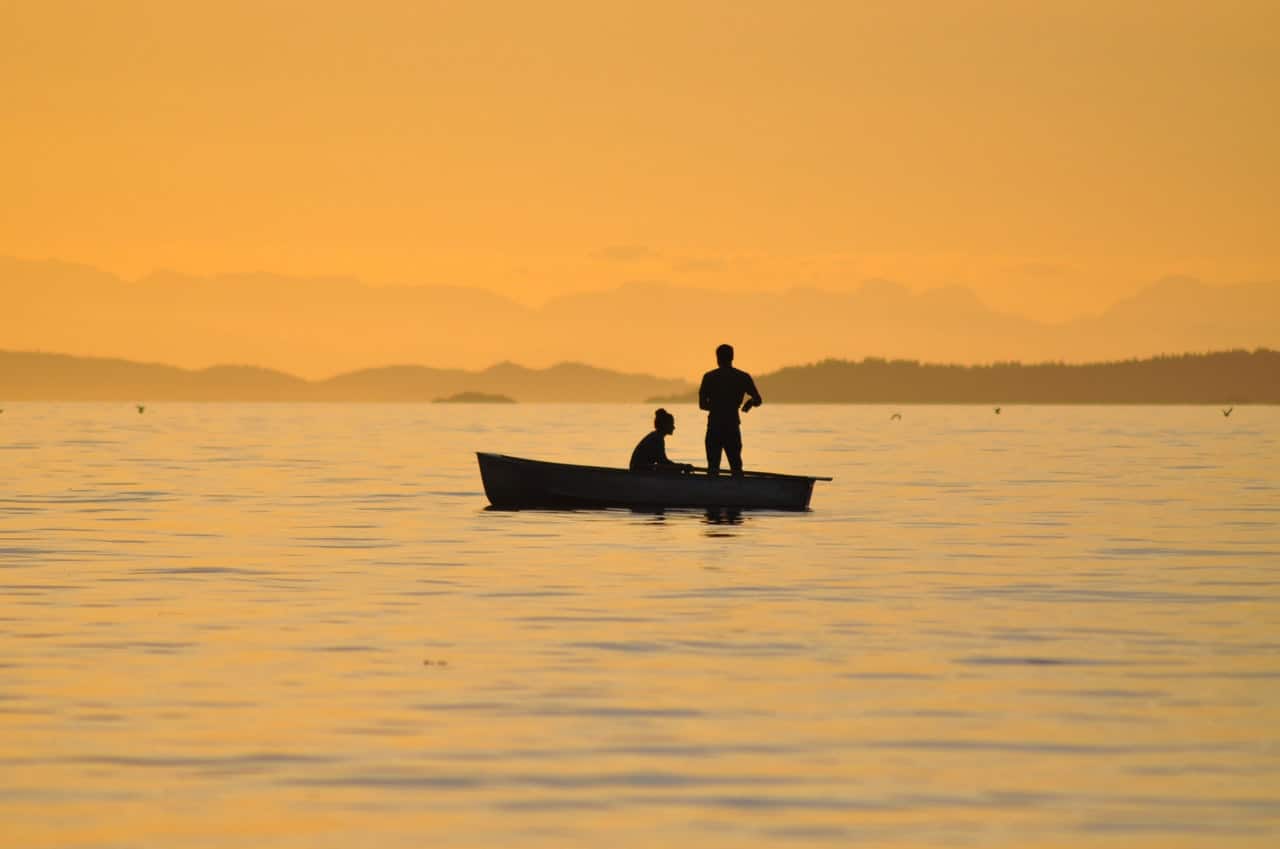 two men in a fishing boat at sunset
