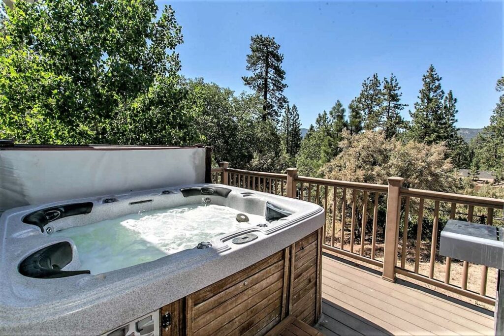 A deck with a hot tub and views of trees